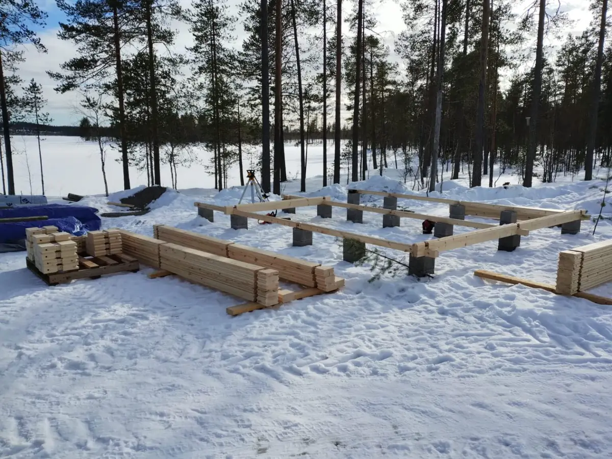 Mökin perustukset lumisella tontilla